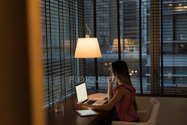 Empresária sentada na cadeira trabalhando em seu laptop no escritório — Fotografia de Stock