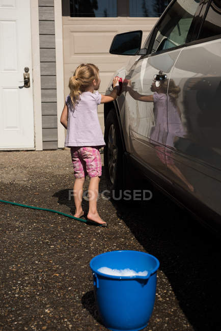 Menina lavando um carro na garagem exterior em um dia ensolarado — Fotografia de Stock
