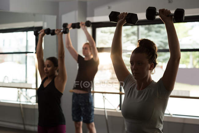 Ajuste as pessoas que se exercitam com halteres no estúdio de fitness . — Fotografia de Stock