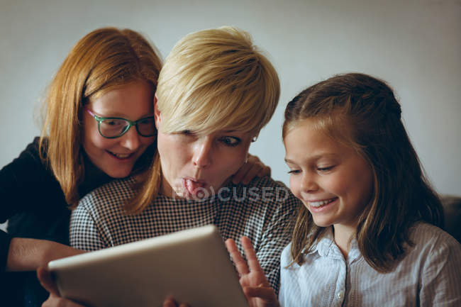Улыбающаяся мать и дети делают селфи с цифровым планшетом дома — стоковое фото