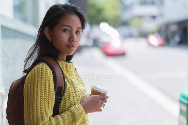 Menina adolescente segurando xícara descartável de café na cidade — Fotografia de Stock