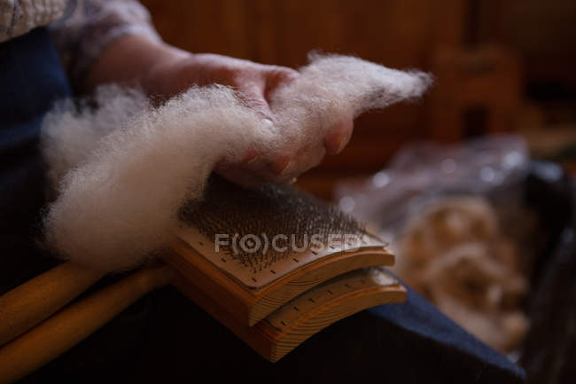 Primer plano de la mujer mayor usando cepillo de tejido en la tienda - foto de stock