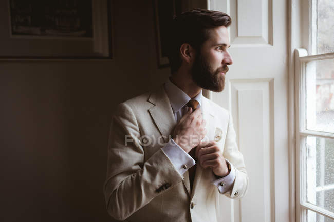 Thoughtful groom looking out of the window at home — Stock Photo