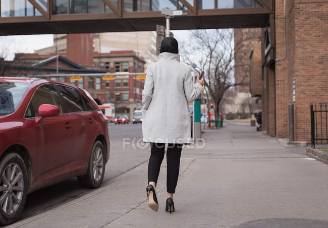 Vue arrière de la femme en hijab marchant dans la rue de la ville — Photo de stock