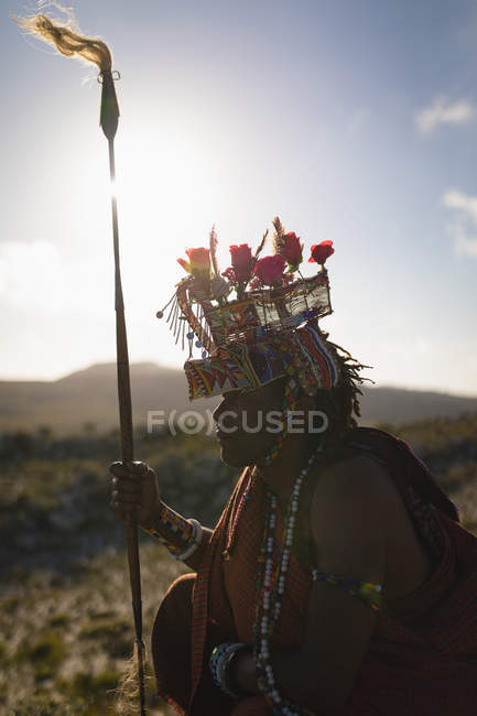 Maasai homem sentado com pau no campo em um dia ensolarado — Fotografia de Stock