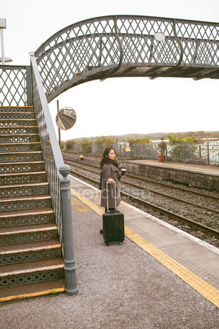 Жінка чекає на поїзд з багажем на залізничній платформі — стокове фото