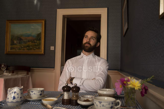 Thoughtful groom sitting in front of meal on table at home — Stock Photo