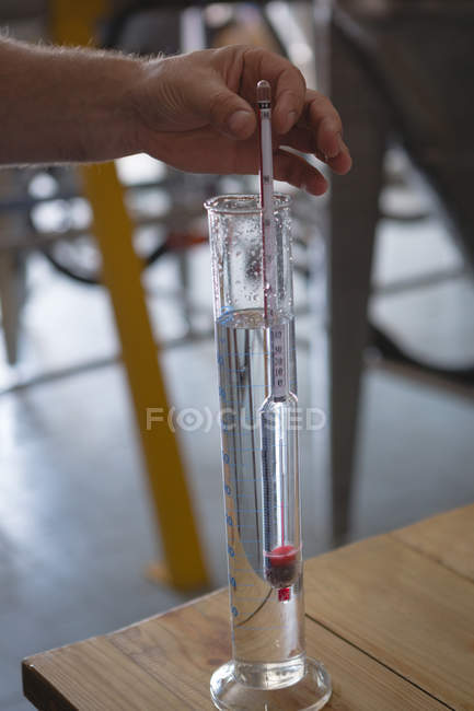Close-up do trabalhador masculino verificando a qualidade do gin na fábrica — Fotografia de Stock