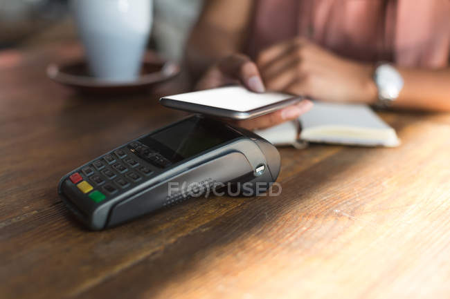 Teenage girl making payment through NFC in restaurant — Stock Photo