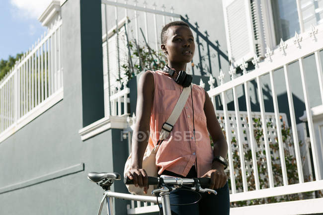 Donna svegliarsi con la bicicletta su un marciapiede in città — Foto stock
