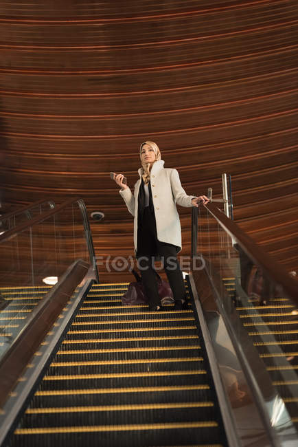 Jovem mulher em hijab descendo da escada rolante — Fotografia de Stock