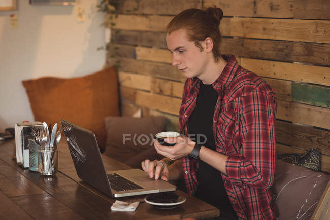 Человек, использующий ноутбук во время кофе в кафе — стоковое фото