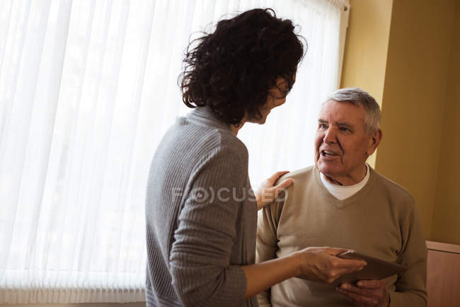 Смотритель показывает цифровые таблетки пожилой женщине в доме престарелых — стоковое фото