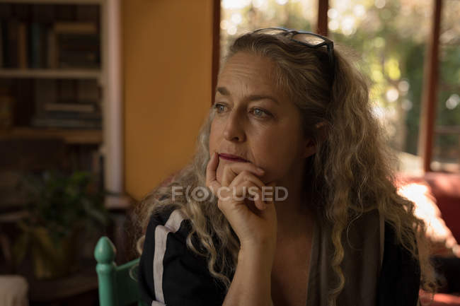 Задумчивая зрелая женщина сидит дома — стоковое фото