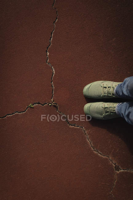 Low section of woman standing in cracked tennis court — Stock Photo
