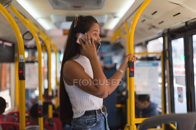 Девушка-подросток разговаривает по мобильному телефону в автобусе — стоковое фото