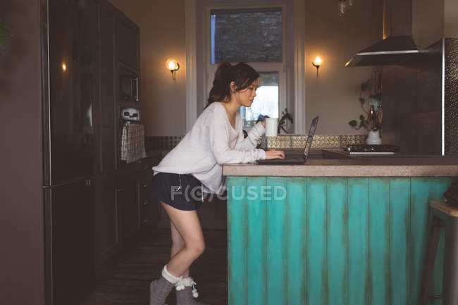 Jeune femme utilisant un ordinateur portable à la maison — Photo de stock