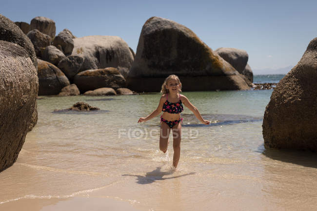 Девушка бежит в море на пляже в солнечный день — стоковое фото