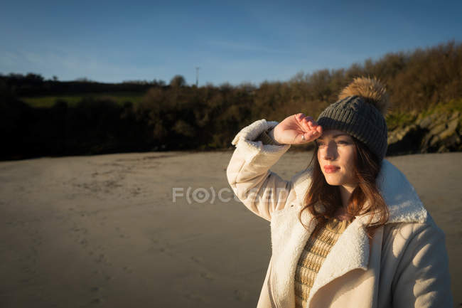 Donna che protegge gli occhi vicino al fiume durante il tramonto . — Foto stock