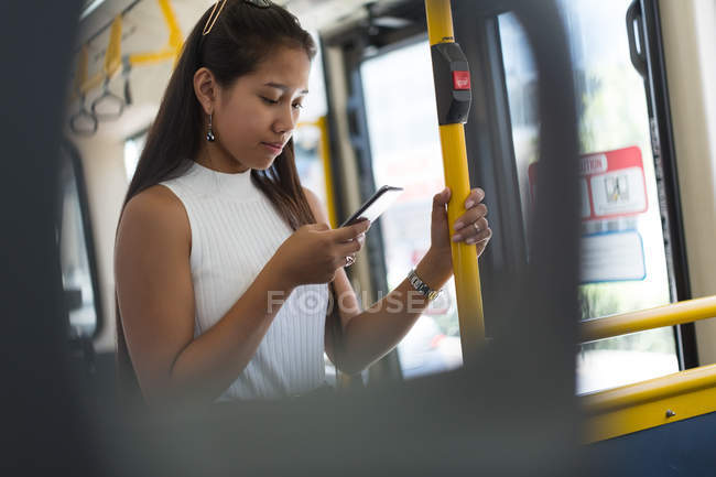 Teenage asian girl using mobile phone in the bus — Stock Photo