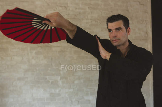 Homem praticando com fã de kung fu em estúdio de fitness . — Fotografia de Stock