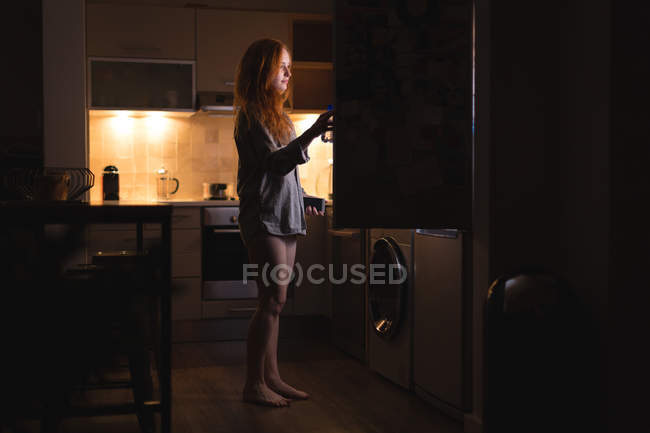 Mujer abriendo un refrigerador en casa - foto de stock