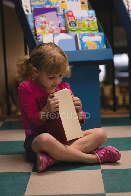 Fille payant avec livre en magasin — Photo de stock