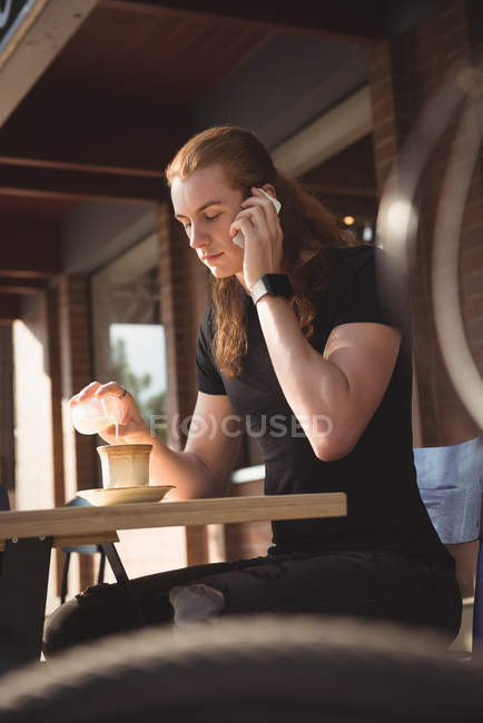 Man talking on mobile phone while having coffee at outdoor cafe — Stock Photo