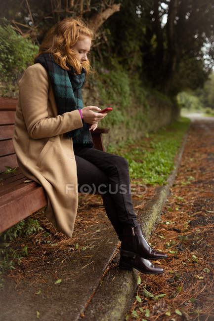 Mujer joven usando el teléfono móvil en el parque - foto de stock
