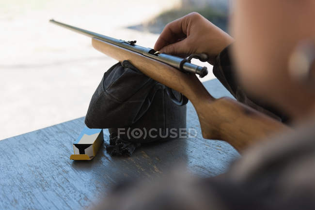 Sección media del hombre cargando bala en la escopeta - foto de stock