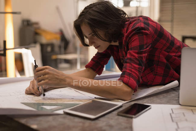 Young female engineer using compass in workshop. — Stock Photo