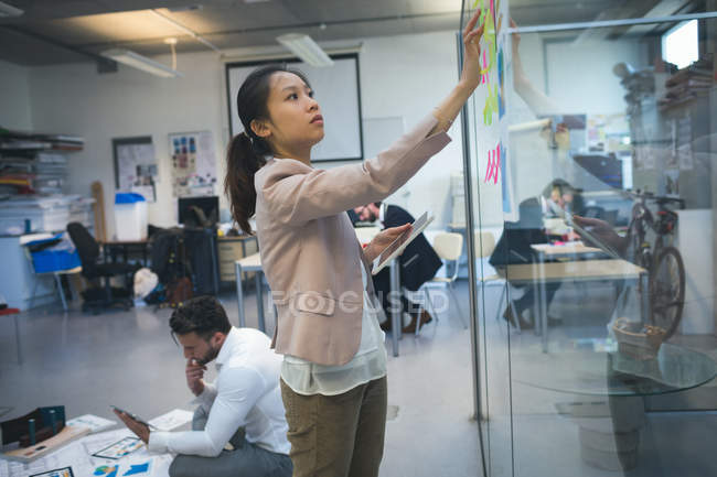 Manager klebt Klebezettel an Glaswand im Büro — Stockfoto
