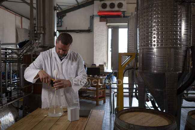 Чоловік працівник перевіряє якість джину на заводі — стокове фото