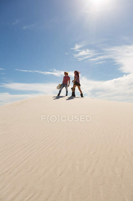 Coppia con lavagna passeggiando in duna di sabbia in una giornata di sole — Foto stock