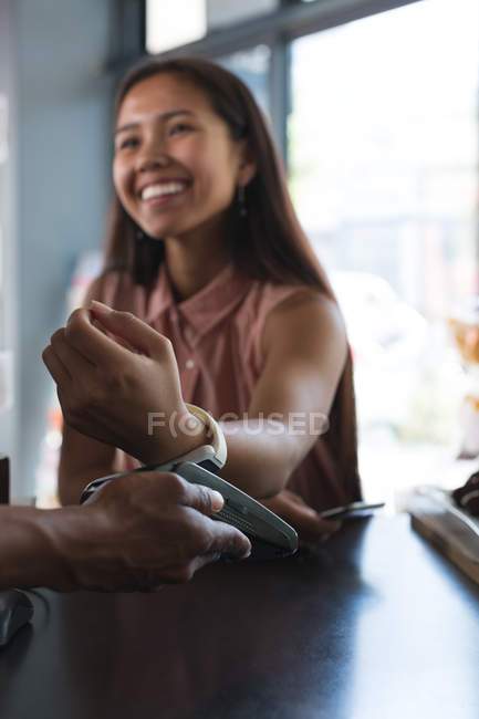 Teenage girl making payment through smartwatch in restaurant — Stock Photo