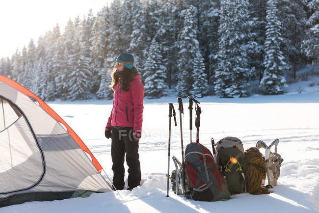 Donna in piedi vicino tenda nel paesaggio innevato durante l'inverno . — Foto stock