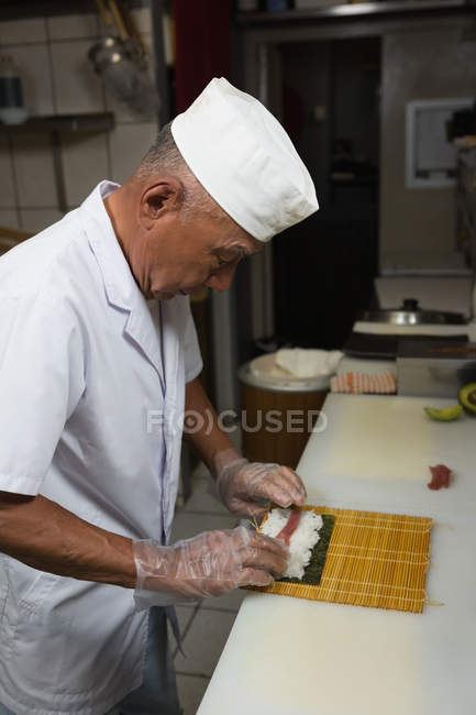 Старший шеф-кухар готує суші на кухні в готелі — стокове фото