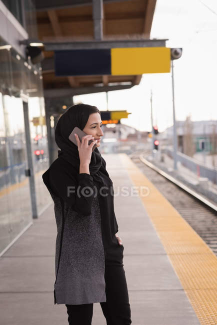 Femme en hijab parlant sur téléphone portable à la gare — Photo de stock