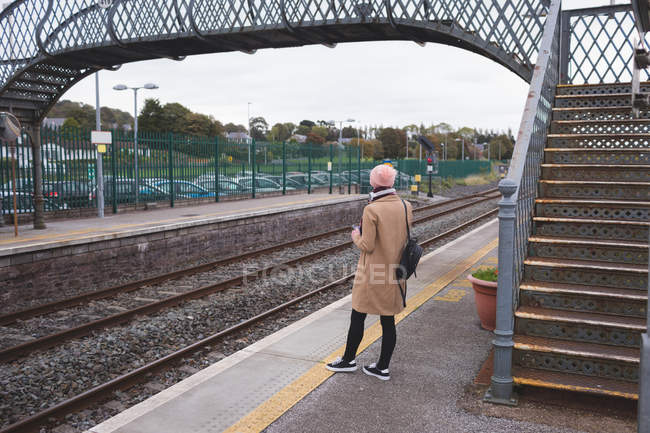 Вид ззаду жінки, що стоїть на залізничній станції — стокове фото