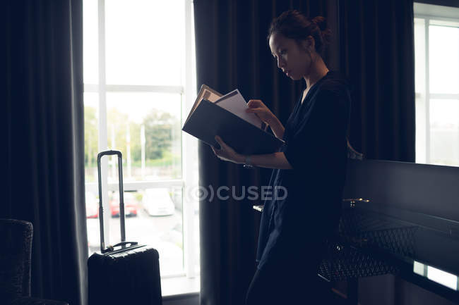 Mujer leyendo documentos en la habitación del hotel - foto de stock