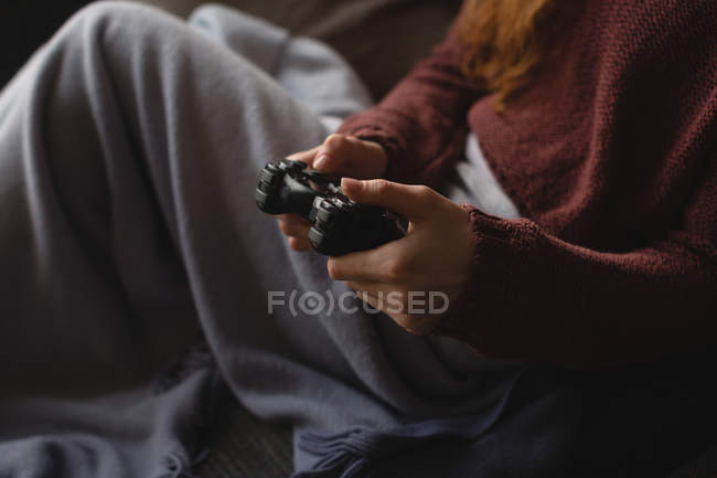 Средняя секция женщины, играющей в видеоигры дома — стоковое фото