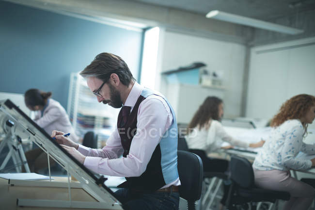 Male executive working over drafting table in modern office — Stock Photo