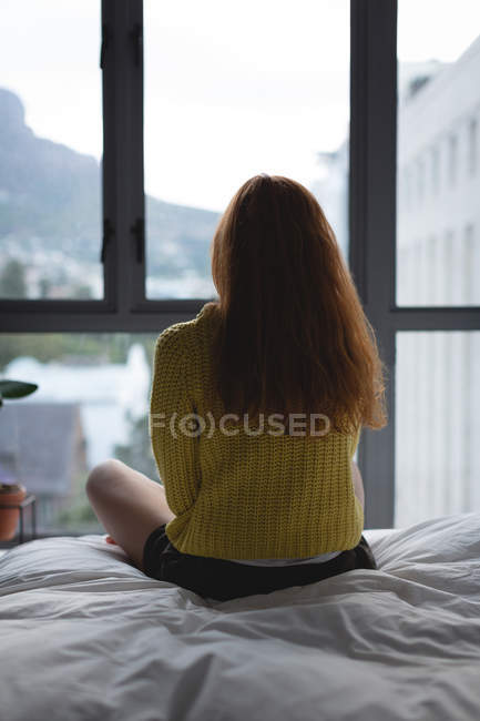 Вид ззаду жінки, що розслабляється в спальні вдома — стокове фото