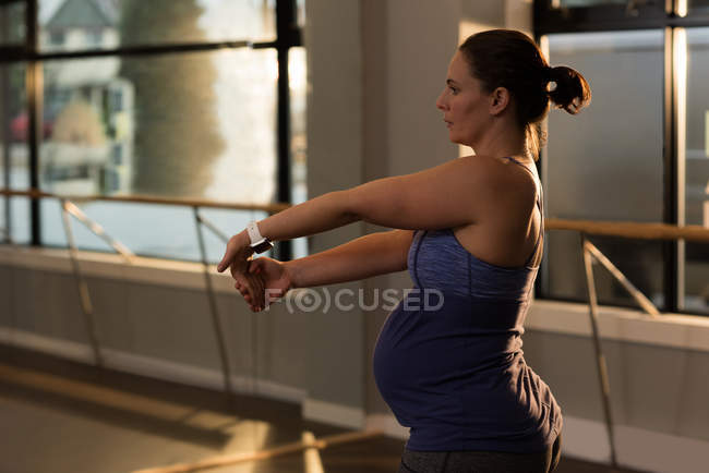 Беременная женщина делает упражнения на растяжку дома — стоковое фото