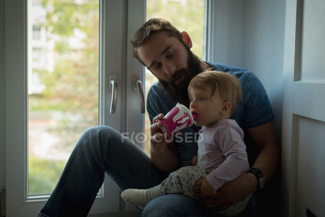Padre alimentando a su hijo en casa - foto de stock