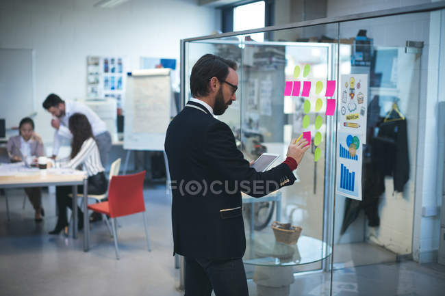 Бизнес-руководитель смотрит на липкие заметки в офисе — стоковое фото