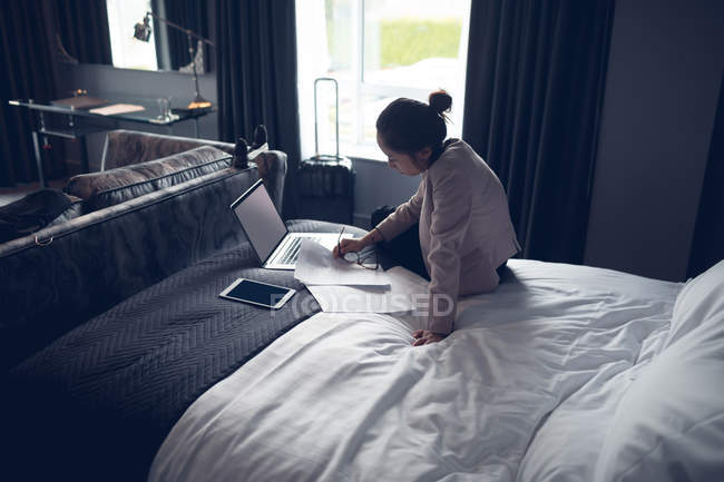 Женщина с помощью ноутбука на кровати в отеле — стоковое фото