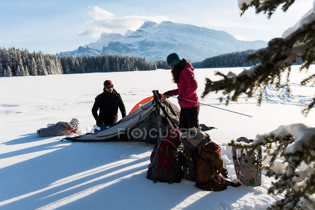 Paar schlägt Zelt in verschneiter Landschaft in den Bergen auf. — Stockfoto