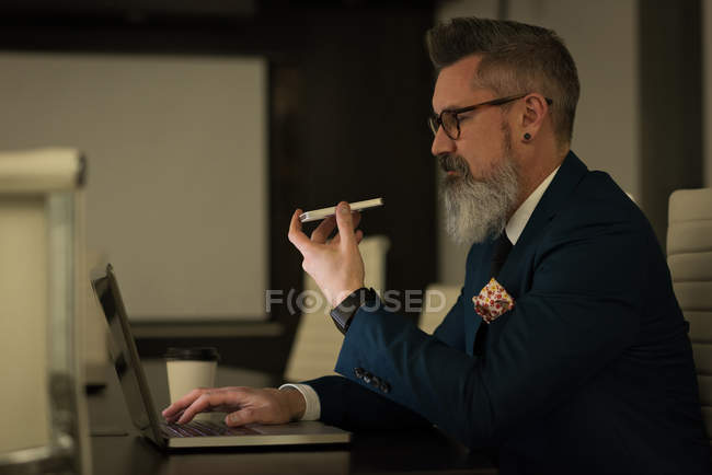 Executivo de negócios falando no celular enquanto usa tablet digital no escritório — Fotografia de Stock