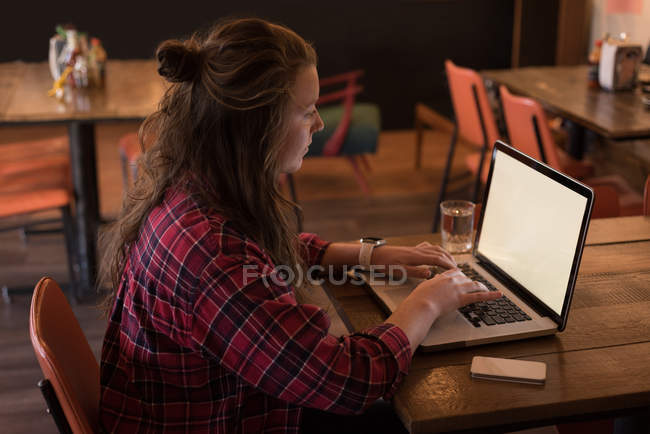Woman working with laptop at table in cafe — Stock Photo